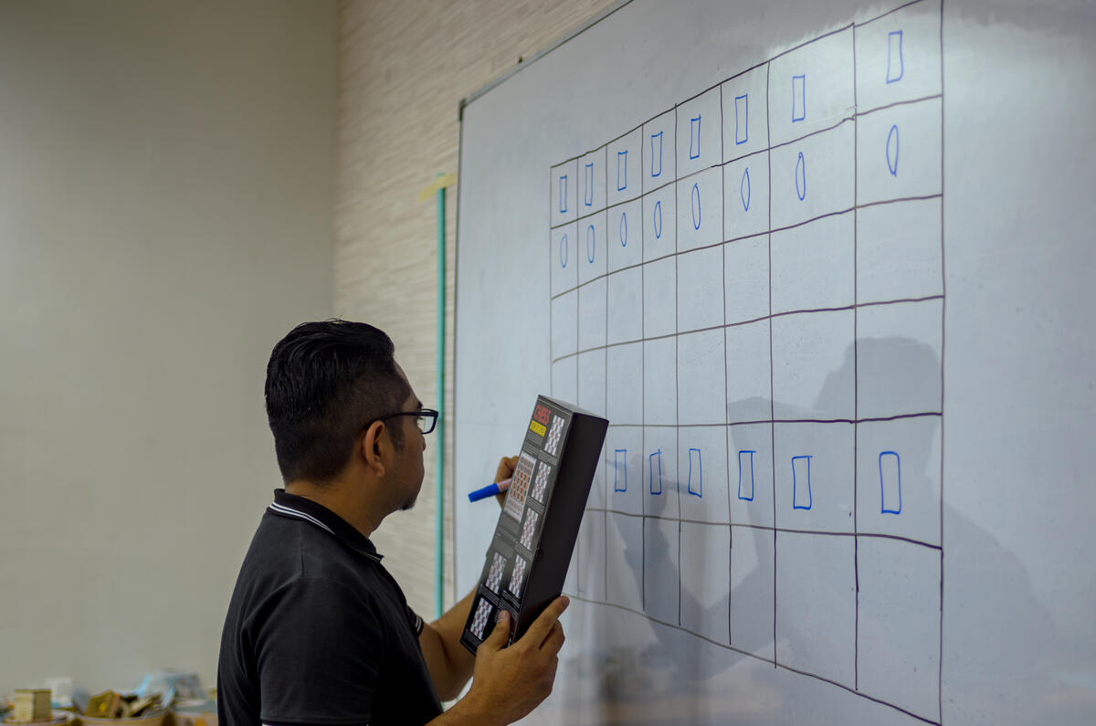 A teacher pointing at the chessboard during a lesson