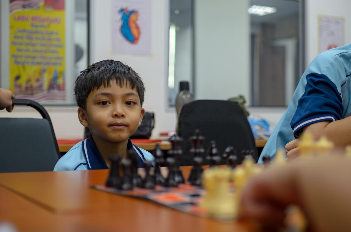 Pupils gathered around a chess game in concentration