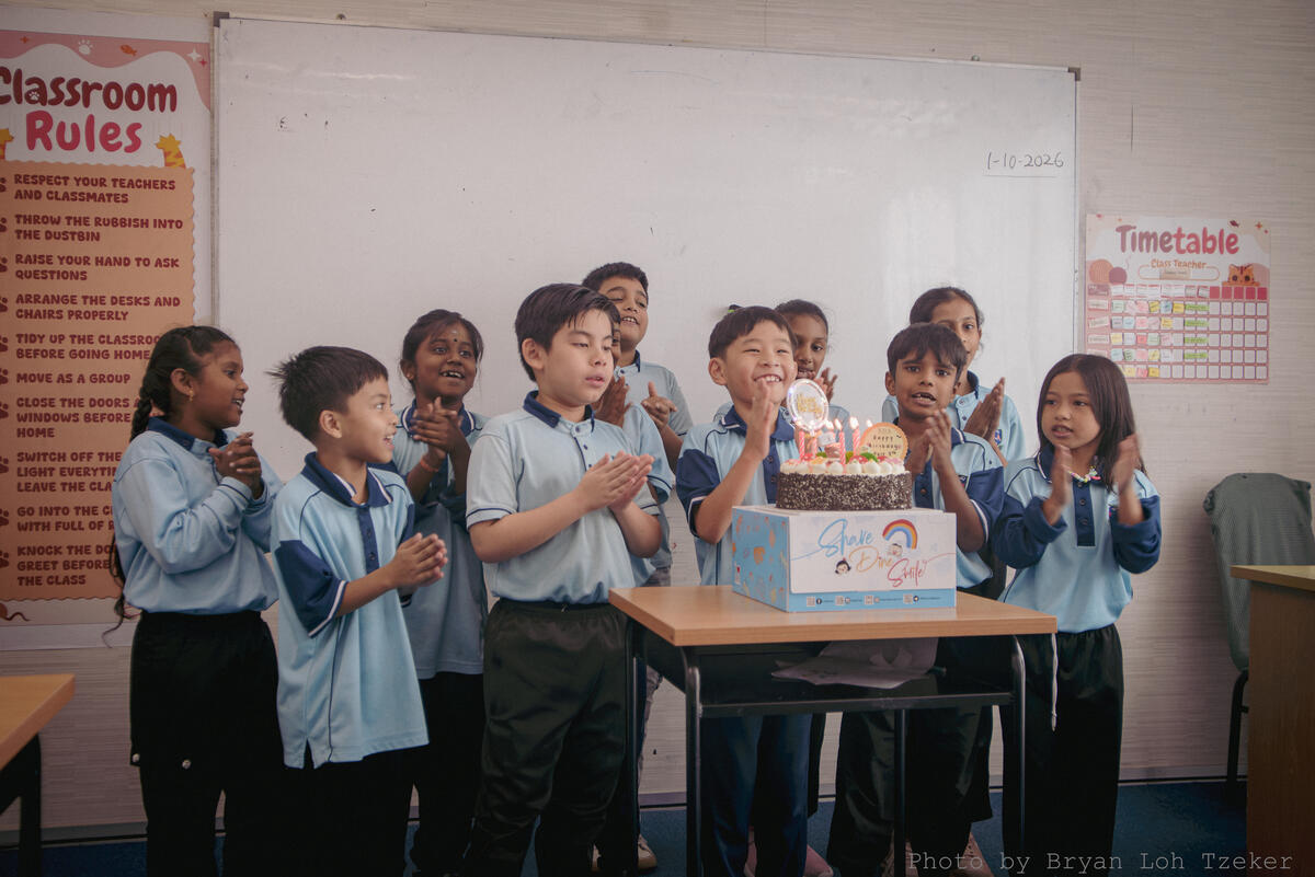 Pupils singing as their classmate blows out the birthday candles