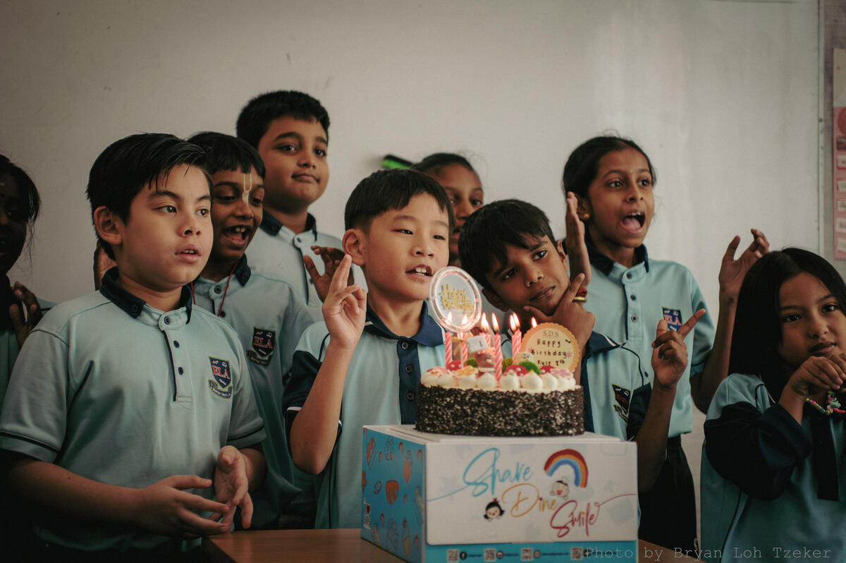 Pupils singing as their classmate blows out the birthday candles