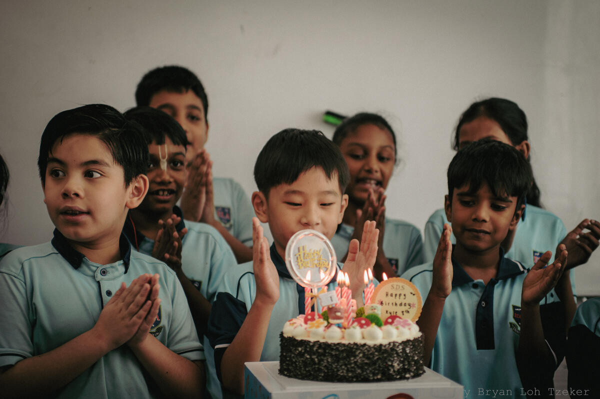 Pupils singing as their classmate blows out the birthday candles