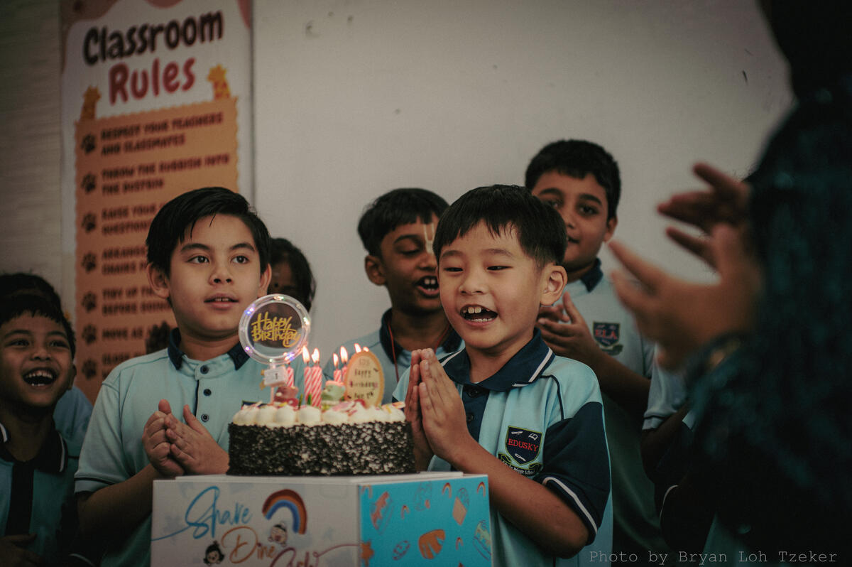 Pupils singing as their classmate blows out the birthday candles