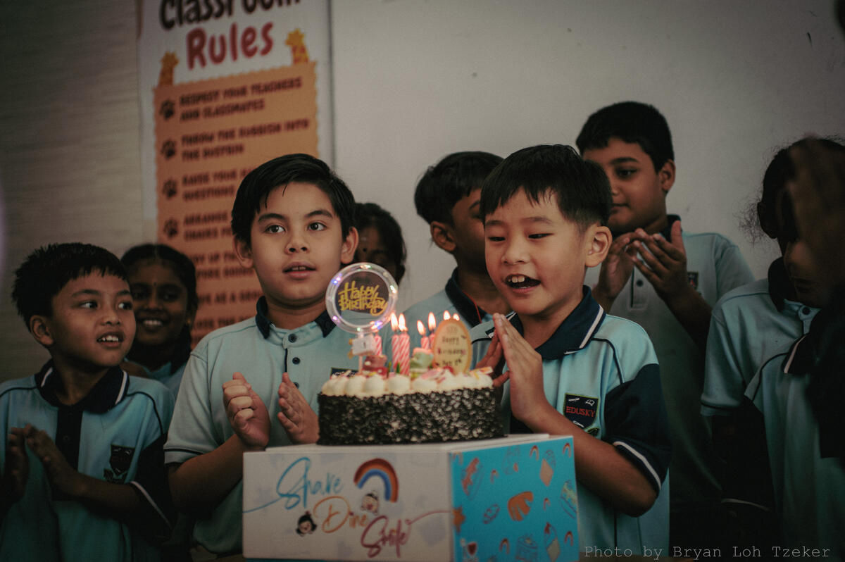 Pupils singing as their classmate blows out the birthday candles