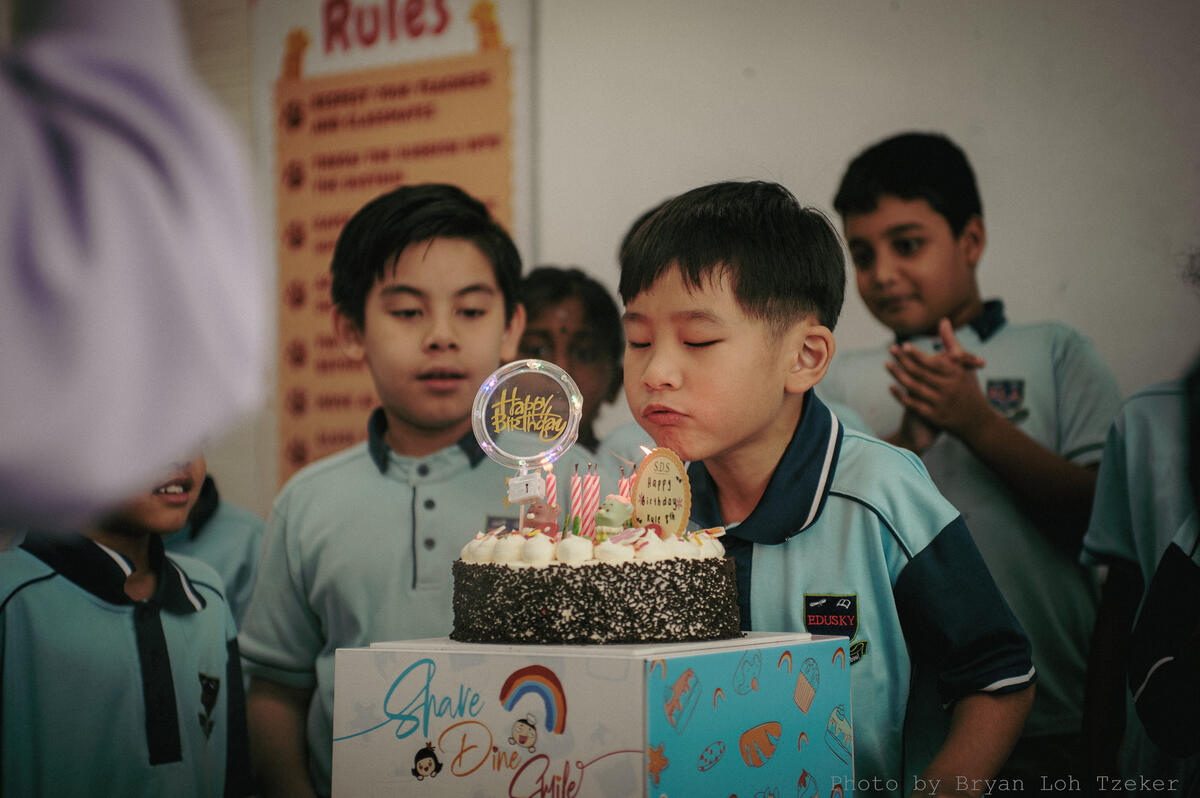 Pupils singing as their classmate blows out the birthday candles