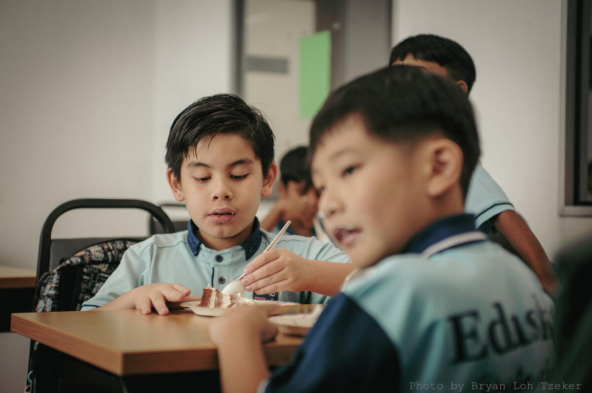 Pupils singing as their classmate blows out the birthday candles