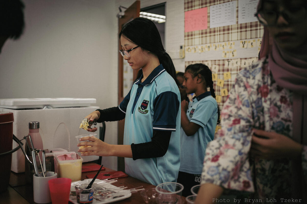 Pupils serving a line of younger customers