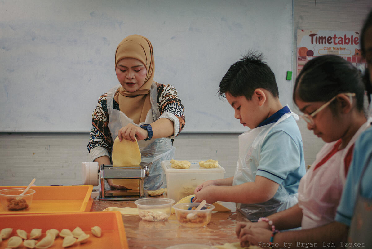 Pupils and teachers cooking side by side for Merdeka
