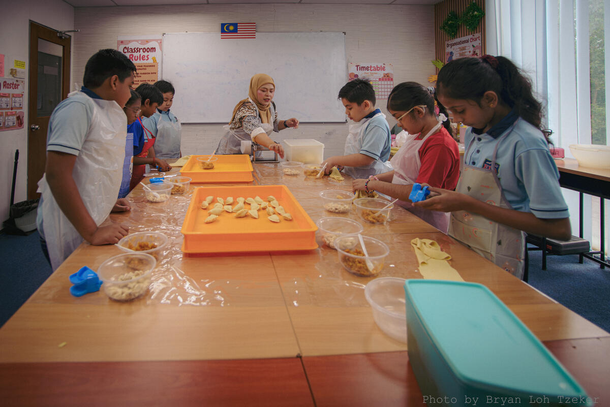 Pupils arranging food on plates for Merdeka