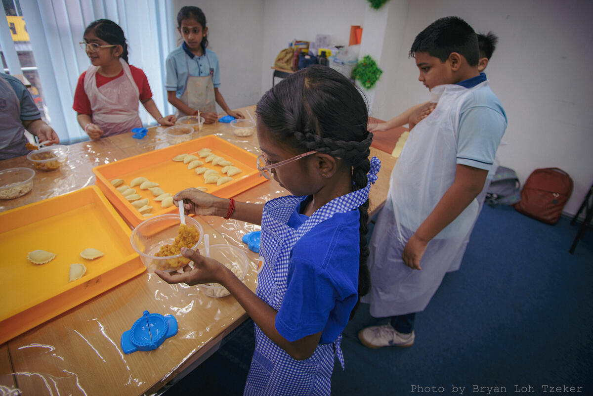 Pupils wrapping food in banana leaf for Merdeka