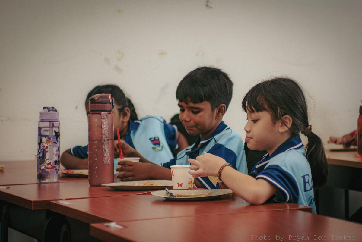 Pupils laughing while eating together at Merdeka
