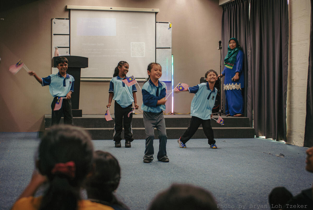 Pupils holding Malaysian flags on stage