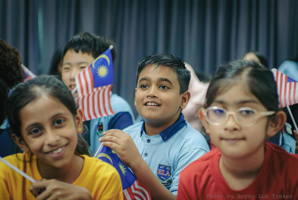 Pupils waving the Jalur Gemilang from the audience