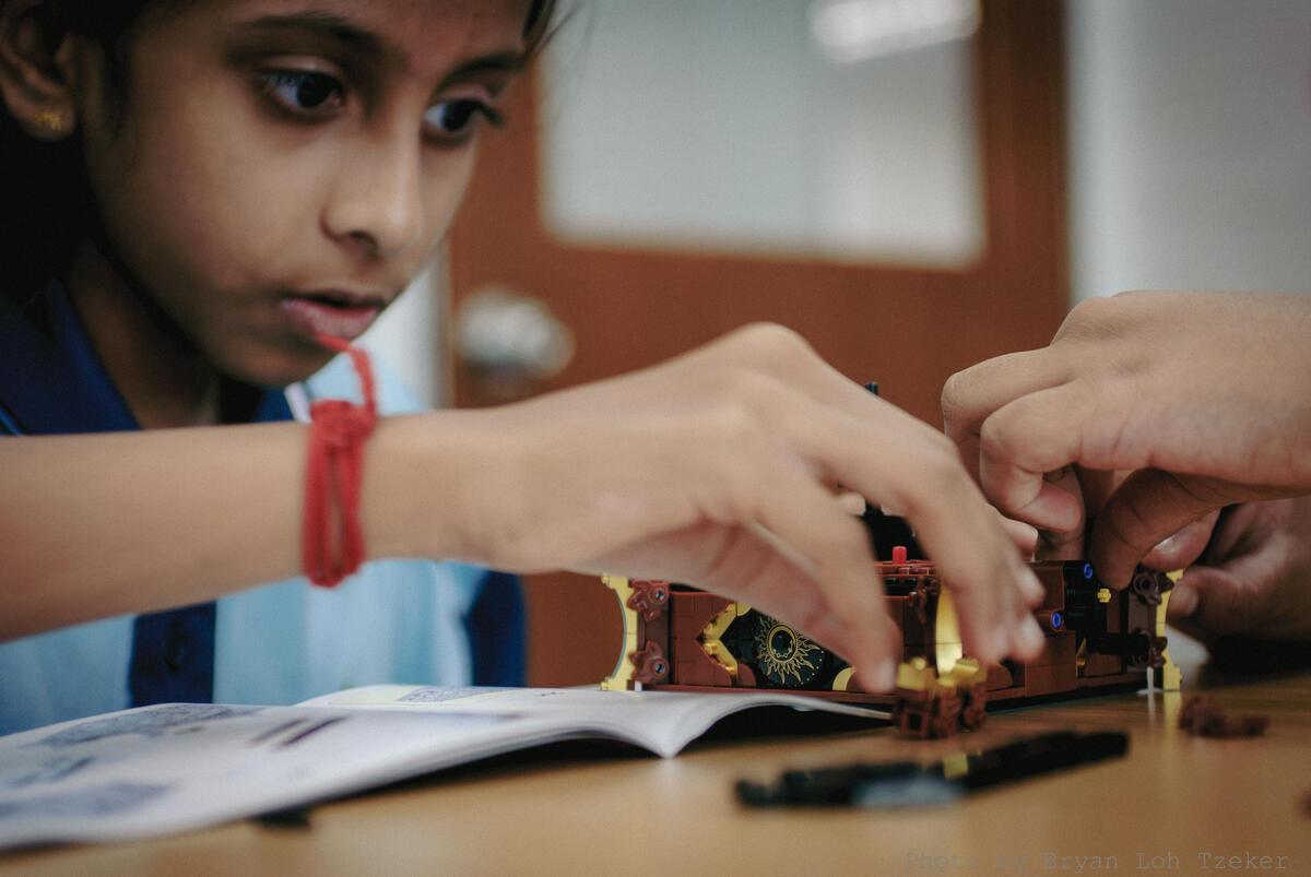 Year 3 pupils taking turns adding Lego bricks