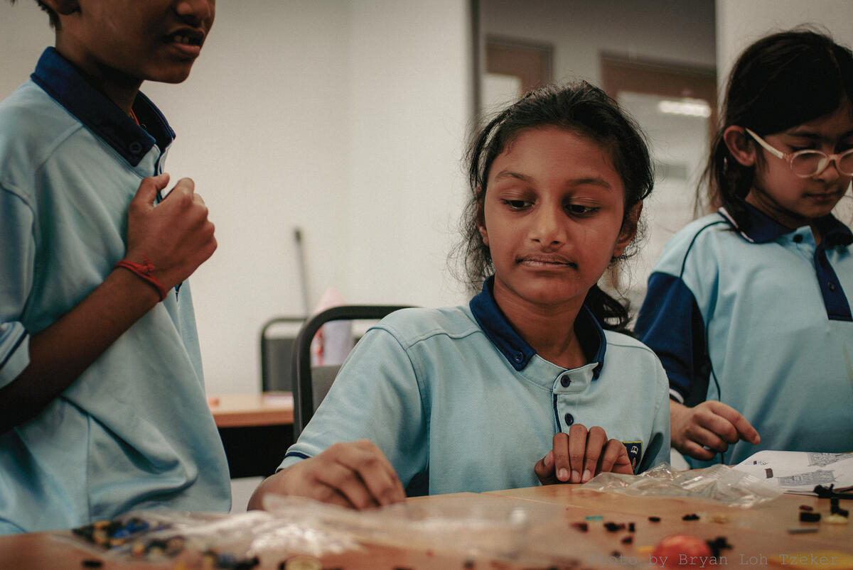 Pupils carefully fitting a small Lego piece into place